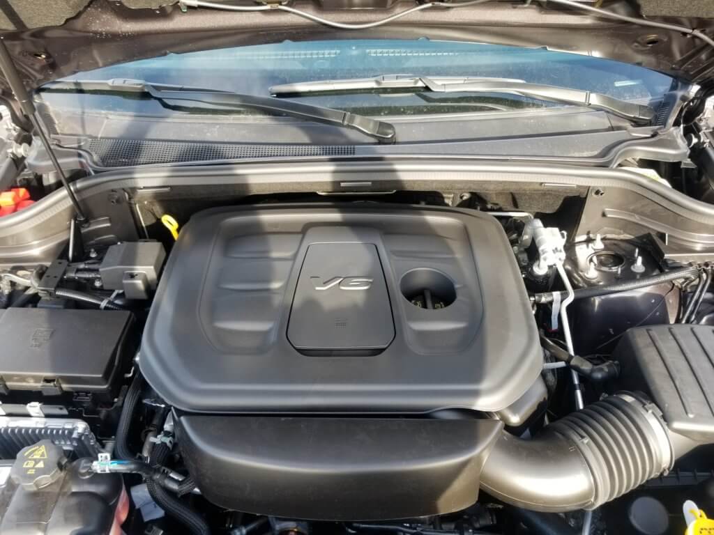 Jeep Grand Cherokee 3.6L engine bay with the engine oil filter access cover pictured in the center